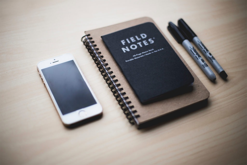 Notebook with phone and pens on a desk