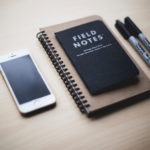 Notebook with phone and pens on a desk